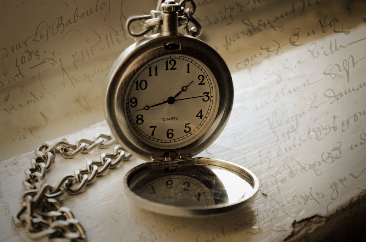 Close-up of a classic pocket watch resting on handwritten script, evoking a sense of nostalgia.