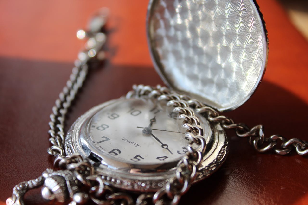 Close-up of a vintage silver pocket watch with chain, elegantly designed.